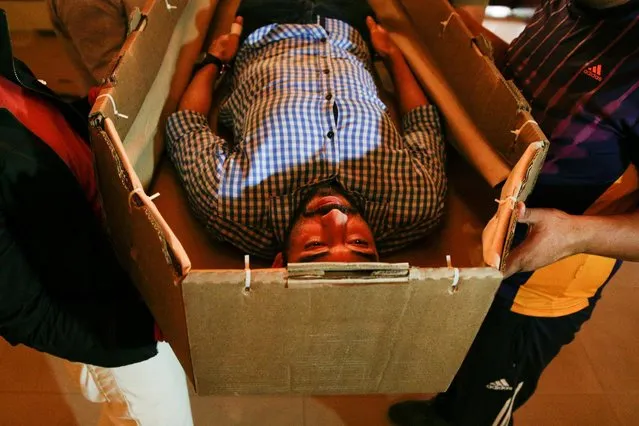 Elio Angulo lies inside a cardboard coffin as he introduces his product to potential customers at a mortuary in Valencia, in the state of Carabobo, Venezuela August 25, 2016. (Photo by Marco Bello/Reuters)