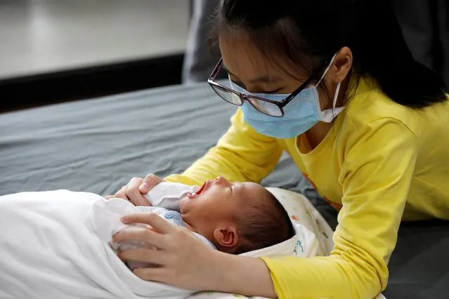Ha Linh Nguyen, wearing a protective mask, watches over her newborn brother Phuc An at home during the coronavirus disease (COVID-19) outbreak in Hanoi, Vietnam April 13, 2020. Phuc An was born at Vinmec hospital in Hanoi on April 1, when the Southeast Asian country started its strict restrictions on movement to contain the spread of the coronavirus that has infected more than 3 million people worldwide. The three-week lockdown put most of the social and economic activities throughout the country on hold, but life must go on, and giving birth couldn't be delayed. (Photo by Kham/Reuters)