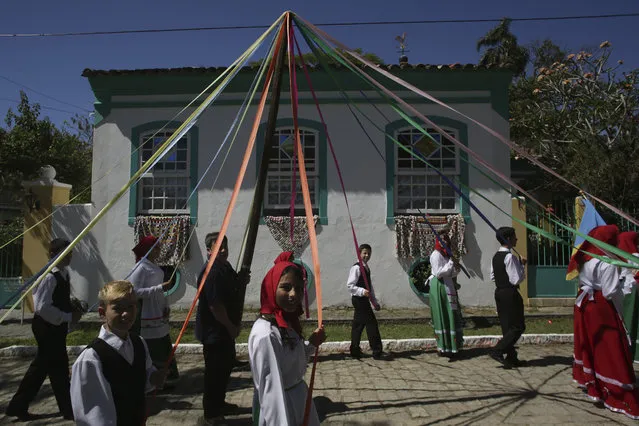 In this November 11, 2017 photo, a folk group performs the ribbon dance around the St. Sebastian pole during the Azorean Culture Festival, which celebrates the culture of the Azores, the Portuguese island chain that lies in the mid-Atlantic, in Enseada de Brito, in Brazil's Santa Catarina southern state. Festival-goers dance around the pole of St. Sebastian, known locally for helping those who are single find their match. (Photo by Eraldo Peres/AP Photo)