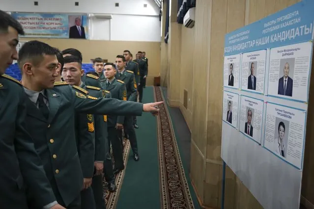 National servicemen lineup to cast their votes next to a poster showing presidential candidates at a polling station in Almaty, Kazakhstan, Sunday, November 20, 2022. Kazakhstan's president appears certain to win a new term against little-known challengers in a snap election on Sunday. Five candidates are on the ballot against President Kassym-Jomart Tokayev, who faced a bloody outburst of unrest early this year and then moved to marginalize some of the Central Asian country's longtime powerful figures. (Photo by Vladimir Tretyakov/NUR.KZ via AP Photo)