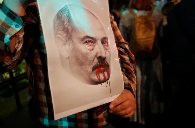 A demonstrator holds a portrait of Belarusian President Alexander Lukashenko during a protest against presidential election preliminary results outside Belarusian embassy in Moscow, Russia on August 11, 2020. (Photo by Maxim Shemetov/Reuters)