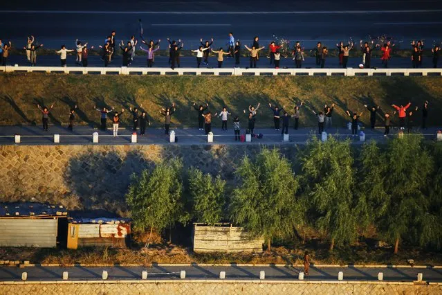 People exercise on banks of Taedong River in Pyongyang, North Korea, early October 9, 2015. (Photo by Damir Sagolj/Reuters)
