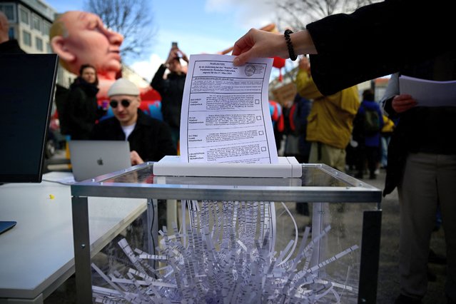 A protestor feed an election ballot in to a shredder machine during a performance in fornt of the Russian embassy in Berlin, where voters lined up to cast their ballots in the Russia's presidential election on March 17, 2024. (Photo by Tobias Schwarz/AFP Photo)