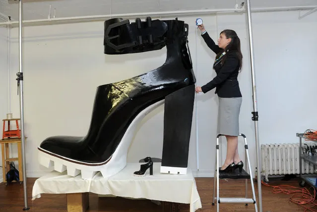 Guinness World Records adjudicator Kim Partrick measures the largest high heeled shoe, standing 6 feet 1 inch tall and 6 feet 5 inches long, Monday, November 10, 2014, in New York. The shoe was created by Jill Martin and Kenneth Cole as part of Guinness World Records Day on November 13.  (Photo by Diane Bondareff/Invision for Guinness World Records/AP Images)