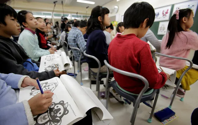 Elementary schoolchildren check three sets of candidates of official mascots for the Tokyo 2020 Olympics and Paralympics at their school in Tokyo Monday, December 11, 2017. Voting by schoolchildren to select the official mascots began Monday across Japan. The results will be announced on Feb. 28. (Photo by Shizuo Kambayashi/AP Photo)