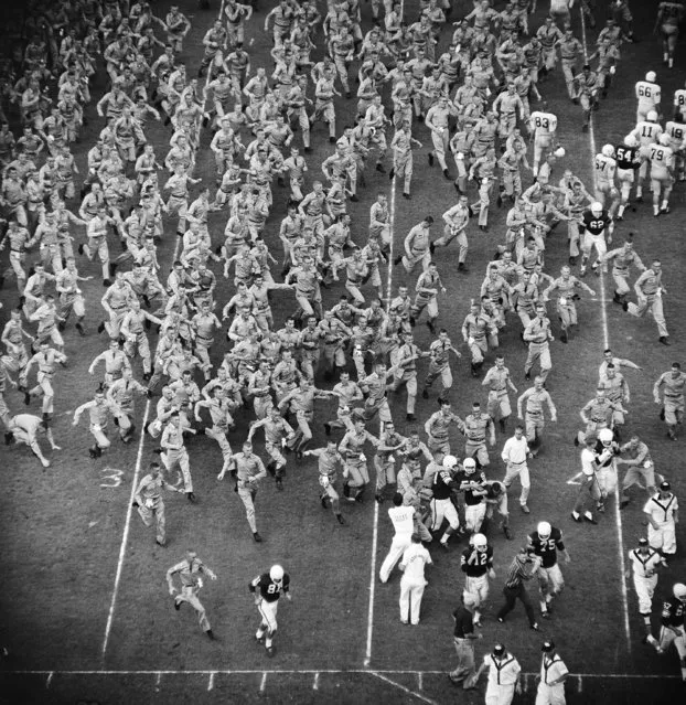 Members of the Texas A&M Cadet Corps swarm onto Kyle Field at College Station, Tex., October 15, 1960, to congratulate members of their football ream who held a favored TCU team to a 14-14 tie. Players identified are quarterback Daryl Keeling (12); tackle Wayland Simmons (75); ends Bobby Huntington and Frank Fisher (89). (Photo by Dave Taylor/AP Photo)