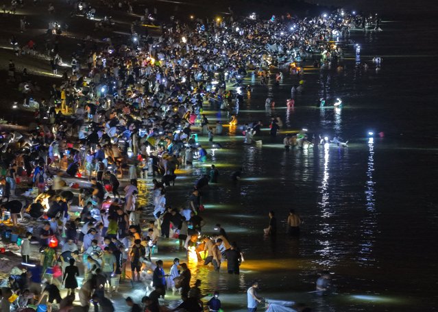 Crowds of locals and tourists with flashlights try to catch noodlefish at the shore on June 29, 2025 in Rizhao, Shandong Province of China. Recently, numerous noodlefish swarmed the shores of Rizhao, drawing large number of tourists and locals. (Photo by VCG/VCG via Getty Images)