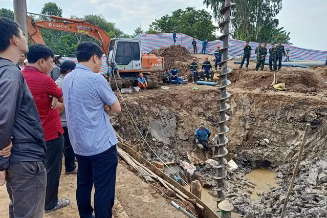 Rescuers look down into the site of where a 10-year-old boy is thought to be trapped in a 35-metre deep shaft at a bridge construction area in Vietnam's Dong Thap province on January 2, 2023. Hundreds of rescuers in Vietnam battled January 2 to free a 10-year-old boy who fell into a 35-metre deep hole on a construction site two days ago. (Photo by AFP Photo/Stringer)