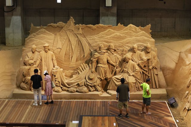 Tourists walk in front of a sand replica during the annual exhibition at Tottori Sand Dune Museum on July 09, 2025 in Tottori, Japan. The 16th exhibition at the Tottori Sand Dune Museum, themed “Traveling the World with Sand and Japan”, features 19 elaborate sand sculptures that depict the country's history and culture to commemorate the World Expo 2025. The exhibition will be on view until April 1, 2026. (Photo by Buddhika Weerasinghe/Getty Images)