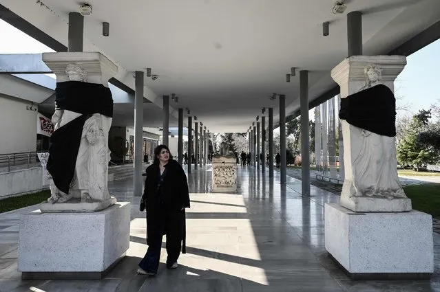 A tourist walks past statues covered with blck cloth at the Archaeological Museum of Thessaloniki on February 13, 2023. Five of largest public museums in Greece are closed on February 13, 2023, due to the 24-hour strike by the Association of Greek Archaeologists. Archaeologists are protesting the draft law tabled by the Culture Ministry and expected to be voted on in Parliament later in the day. The draft law regards the change of the operating status of the museums into Legal Entities under Public Law. (Photo by Sakis Mitrolidis/AFP Photo)