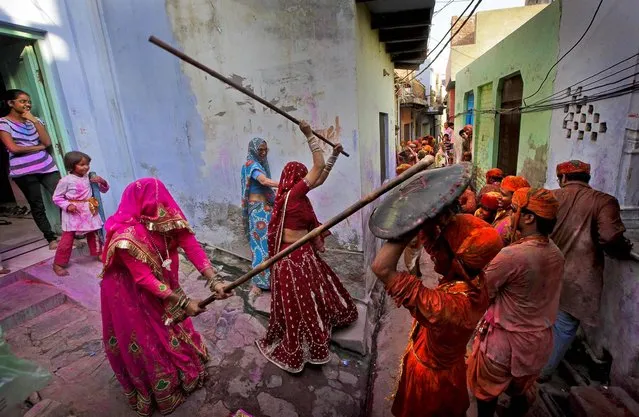 Woman from the village of Barsana hit villagers from Nandgaon with wooden sticks during the Lathmar Holy festival, on March 21, 2013. (Photo by Manish Swarup/Associated Press)