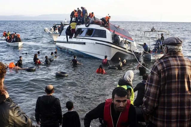 Volunteers and local residents help refugees and migrants disembark from a small vessel after their arrival in Skala Sykaminias on the northeastern Greek island of Lesbos on Friday, October 30, 2015. Greek authorities say 21 people have died in other islands after two boats carrying migrants and refugees from Turkey to Greece sank overnight, in the latest deadly incidents in the eastern Aegean Sea. (Photo by Kostis Ntantamis/AP Photo)