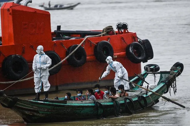 Volunteers wearing personal protective equipment (PPE) on a boat transfer people suspected of having the COVID-19 coronavirus to a quarantine centre in Yangon on October 12, 2020. (Photo by Ye Aung Thu/AFP Photo)