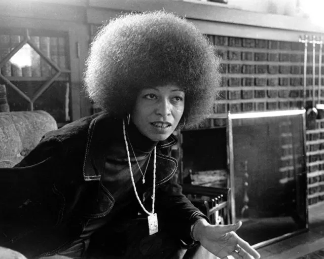 Black militant Angela Davis is seen at home in East Oakland, Calif. on September 9, 1974. She wears two chains representing her commitment to struggle.  One is gold, with the hammer and sickle of the Communist Party. The other is ivory with a dragon, ancient symbol of strength and harbinger of revolution. (Photo by AP Photo)