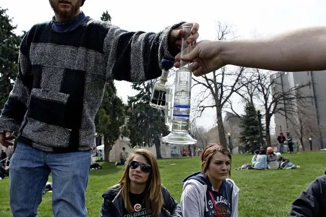 Marijuana smokers pass a bong at the Denver 4/20 pro-marijuana rally at Civic Center Park in Denver on Saturday, April 20, 2013. Authorities generally look the other way at public pot smoking here on April 20. Police said this week they're focused on crowd security in light of attacks that killed three at the finish line of the Boston Marathon. (Photo by Brennan Linsley/AP Photo)