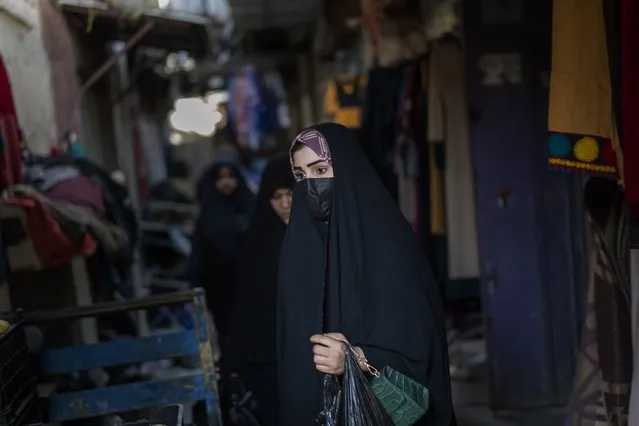 A woman walks through the narrow streets of Alsadria neighborhood in Baghdad, Iraq, Monday, February 27, 2023. For Iraqis, the trauma from the war and U.S. occupation launched twenty years ago is undeniable – an estimated 300,000 Iraqis were killed between 2003 and 2019, according to the Watson Institute for International and Public Affairs at Brown University, as were more than 8,000 U.S. military, contractors and civilians. (Photo by Jerome Delay/AP Photo)