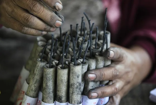 A worker carefully puts the wick on some firecrackers as they make pyrotechnics at a makeshift factory in Bocaue town, Bulacan province, north of Manila December 27, 2014. (Photo by Romeo Ranoco/Reuters)