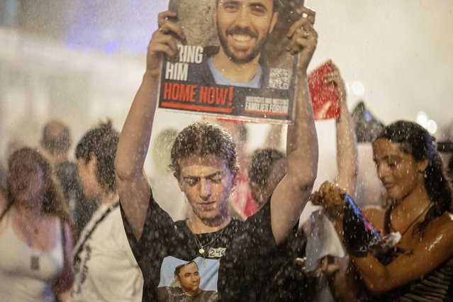Protesters hold posters as Israeli police deploy a water cannon, at a demonstration against Prime Minister Benjamin Netanyahu's government and a call for the release of hostages in Gaza, amid the Israel-Hamas conflict, in Tel Aviv, Israel on June 8, 2024. (Photo by Marko Djurica/Reuters)