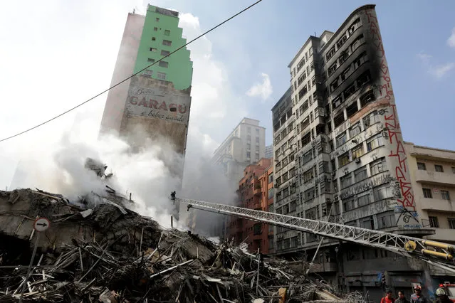 Firefighters try to extinguish a fire at a building in downtown Sao Paulo, Brazil on May 1, 2018. A 24- storey building in the center of Sao Paulo, Brazil's biggest city, collapsed early May 1 after a blaze that rapidly tore through the structure, reportedly killing one person. Dozens of homeless families were squatting in the building, according to local media. (Photo by Paulo Whitaker/Reuters)
