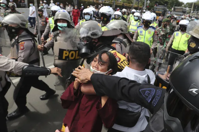 Supporters of Rizieq Shihab, leader of the Islam Defenders Front, scuffle with police officers during a rally in Jakarta, Indonesia, Friday, December 18, 2020. Hundreds of protesters marched in Indonesia's capital on Friday to demand the release of the firebrand cleric who is in police custody on accusation of inciting people to breach pandemic restrictions and ignoring measures to curb the spread of COVID-19 by holding several events, and justice for his six followers who were killed in a shootout with the police. (Photo by Tatan Syuflana/AP Photo) 