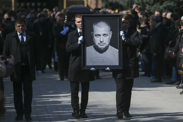 Cemetery workers carry a portrait of slain Russian military blogger Vladlen Tatarsky, during a funeral ceremony at the Troyekurovskoye cemetery in Moscow, Russia, Saturday, April 8, 2023. (Photo by Anton Velikzhanin, M24/Moscow News Agency via AP Photo)