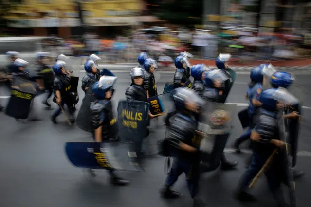 An image taken with a slow shutter speed shows anti-riot police officers moving to another position during a protest near the US Embassy in Manila, Philippines, 27 October 2016. Hundreds of protesters including Indigenous People, students and militant groups marched towards the US Embassy to protest against the presence of US military troops and condemning the violent dispersal on 19 October which left at least forty people hurt including twenty police officers and three people who were run over by a police van. (Photo by Mark R. Cristino/EPA)