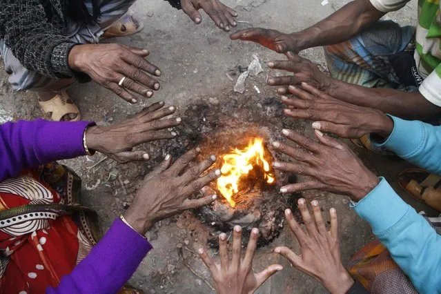Bangladeshi workers warm themselves around a bon-fire in Dhaka on January 8, 2018. Bangladesh recorded its lowest ever temperature in history at 2.6 degrees in Tetulia, Panchagarh under the influence of a severe cold wave prevailing through the northern districts. (Photo by Rehman Asad/AFP Photo)