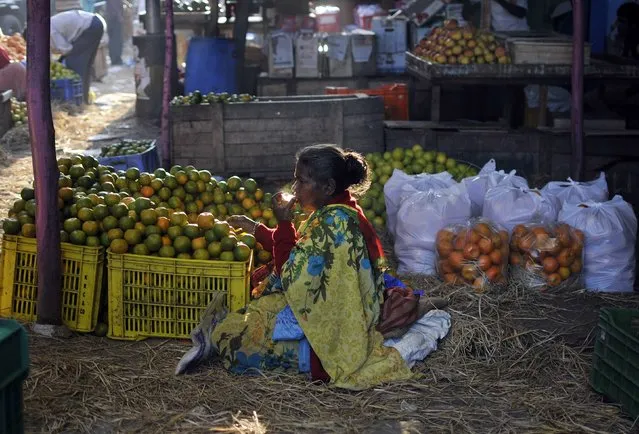 A vendor selling oranges drinks tea as she waits for customers at a fruit market in the southern Indian city of Bengaluru, previously known as Bangalore, January 12, 2015. (Photo by Abhishek N. Chinnappa/Reuters)