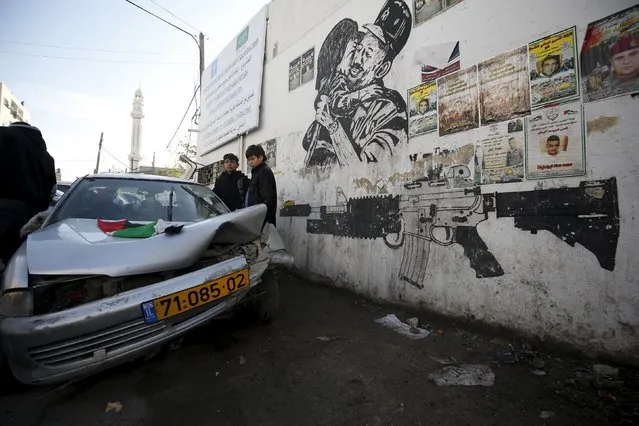 Palestinians gather around a damaged car which Israeli army said was used by Palestinians in an attempt to ram Israeli security forces during an arrest raid in the Qalandia refugee camp, near the West Bank city of Ramallah December 16, 2015. (Photo by Mohamad Torokman/Reuters)