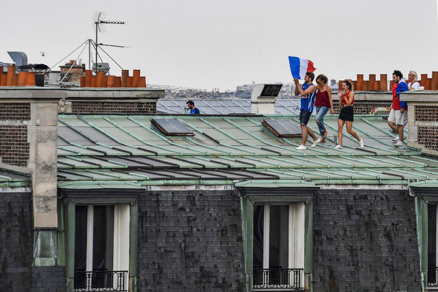 This picture taken from the terrace of the Publicis drugstore in Paris on July 15, 2018 shows people celebrating on the roof of a building, after France won the Russia 2018 World Cup final football match between France and Croatia. (Photo by Gerard Julien/AFP Photo)