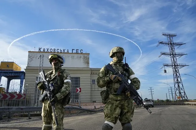 Russian troops guard an entrance of the Kakhovka Hydroelectric Station, a run-of-river power plant on the Dnieper River in Kherson region, south Ukraine, Friday, May 20, 2022. The Kherson region has been under control of the Russian forces since the early days of the Russian military action in Ukraine. This photo was taken during a trip organized by the Russian Ministry of Defense. (Photo by AP Photo/Stringer)