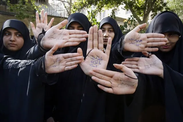 Iranian students display slogans written on their hands during a demonstration denouncing the burning in Sweden of the Koran, Islam's holy book, in front of Swedish embassy in Tehran on July 21, 2023. Demonstrators marched in the Iraqi and Iranian capitals on July 21 to denounce Sweden's permission for protests that desecrate the Koran, as Stockholm withdrew staff from its Baghdad embassy. (Photo by AFP Photo/Stringer)