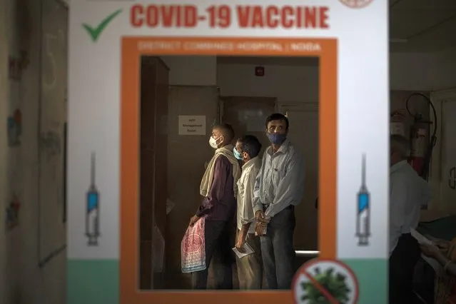 People wait to get their vital signs checked before receiving the COVID-19 vaccine at a government hospital in Noida, a suburb of New Delhi, India, Thursday, April 1, 2021. India is accelerating its vaccination drive by opening it up for everyone above 45 years just as cases spike sharply after several months. (Photo by Altaf Qadri/AP Photo)