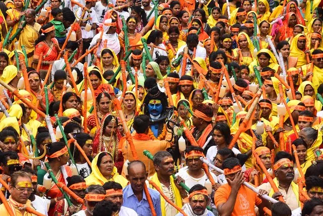 Kanwariyas, devotees of the Hindu deity Shiva, carry holy water from the river Narmada as they take part in a ritualistic walk through a street in Jabalpur on August 7, 2023. Kanwariyas take part in a journey on foot to carry holy water from holy rivers to temples in their home towns in an effort to fulfil wishes and endear them to the Hindu deity Shiva. (Photo by Uma Shankar Mishra/AFP Photo)