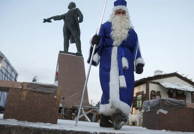 An actor dressed as Grandfather Frost, the Russian Santa Claus, walks next to a statue of Soviet Union founder Vladimir Lenin during celebration of Orthodox Christmas in St.Petersburg, Russia, Thursday, January 7, 2016. (Photo by Dmitry Lovetsky/AP Photo)