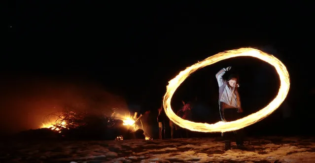In this photo taken with a long exposure photo, a child spins a ball of fire during rituals in celebration of Mesni Zagovezni (Shrovetide) in the village of Lozen near the capital Sofia, Sunday, February 15, 2015. People in the region believe they can chase away evil spirits  by performing fire rituals on Mesni Zagovezni. (Photo by Valentina Petrova/AP Photo)