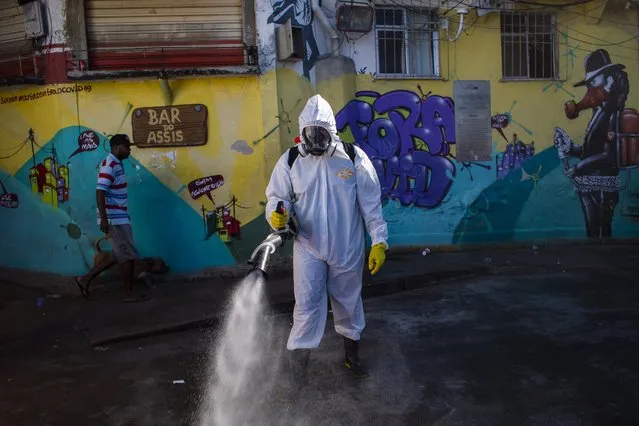 Thiago Firmino sprays disinfectant in an alley to help contain the spread of the new coronavirus, in the Santa Marta slum of Rio de Janeiro, Brazil, Saturday, April 24, 2021. (Photo by Bruna Prado/AP Photo)