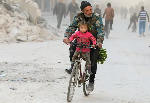 A man rides with his daughter on a bicycle in a rebel-held besieged area of Aleppo, Syria November 23, 2016. (Photo by Abdalrhman Ismail/Reuters)