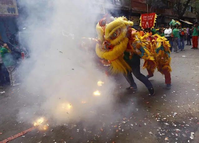 Firecrackers explode as members of the Chinese community perform a lion dance during the Chinese Lunar New Year celebrations in Kolkata February 19, 2015. (Photo by Rupak De Chowdhuri/Reuters)
