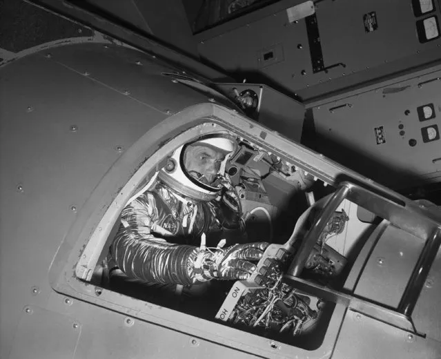 In this January 11, 1961 file photo, Marine Lt. Col. John Glenn reaches for controls inside a Mercury capsule procedures trainer as he shows how the first U.S. astronaut will ride through space during a demonstration at the National Aeronautics and Space Administration Research Center in Langley Field, Va. (Photo by AP Photo)