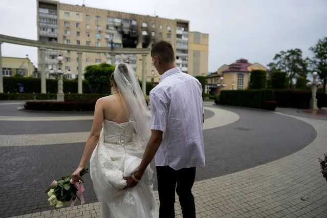Yevhen Levchenko and Nadiia Prytula leave after getting married in Irpin, on the outskirts of Kyiv, Ukraine, Tuesday, June 21, 2022. After the wedding the couple must separate, Nadiia goes to study abroad and Yevhen stays because men cannot leave the country. A growing number of couples in Ukraine are speedily turning love into matrimony because of the war with Russia. Some are soldiers, marrying just before they head off to fight. Others are united in determination that living and loving to the full are more important than ever in the face of death and destruction. (Photo by Natacha Pisarenko/AP Photo)