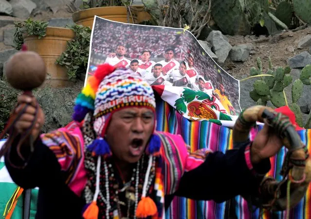 A shaman performs a good luck ritual in front of a photo of Peru's national soccer team, on San Cristobal hill in Lima, Peru, Friday, June 10, 2022. The shamans called on Mother Earth to support the Andean nation in its play-off game against Australia on Monday, to seal one of the final spots in this year's World Cup in Qatar. (Photo by Martin Mejia/AP Photo)