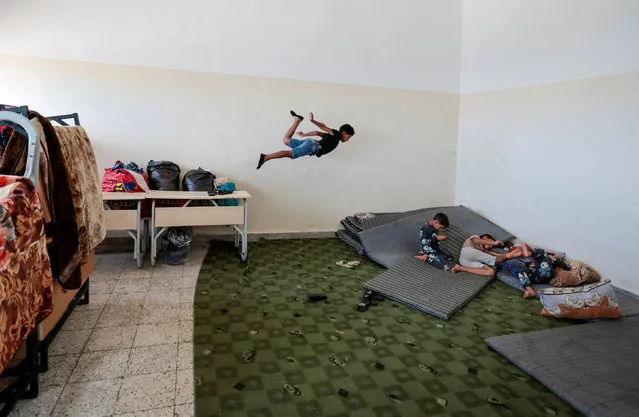 A boy, who survived the deadly storm that hit Libya,  jumps as he plays with his brothers  inside  a classroom at Um almoumanen school, where they take shelter in Derna, Libya on September 20, 2023. (Photo by Zohra Bensemra/Reuters)