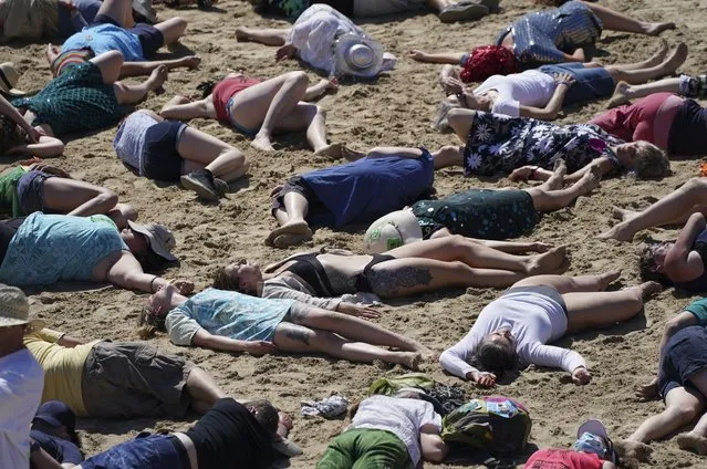 Protestors take part in a die-in during a demonstration on a beach outside the G7 meeting in St. Ives, Cornwall, England, Sunday, June 13, 2021. (Photo by Jon Super/AP Photo)