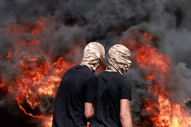 Palestinians burn tyres amid clashes with Israeli security forces during the funeral of 19-year-old Labib Damidi in the occupied West Bank town of Huwara on October 6, 2023. Palestinian Damidi was killed early on October 6 during clashes with Israeli soldiers and settlers in a town that has been the scene of frequent violence in the occupied West Bank, multiple sources said. (Photo by Jaafar Ashtiyeh/AFP Photo)