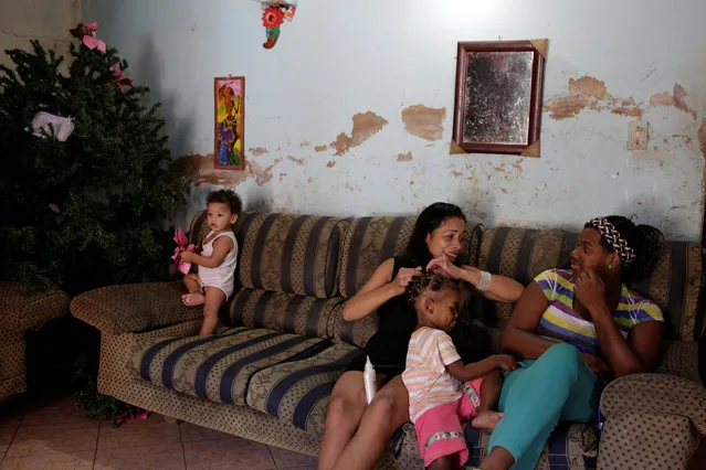 Women talk next to a Christmas tree in their home at the slum of Petare in Caracas, Venezuela December 23, 2016. (Photo by Marco Bello/Reuters)
