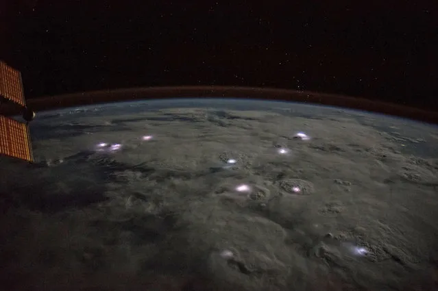 The International Space Station flies approximately 250 miles over thunderstorms visible during a nighttime pass. Lightning can be seen flashing brightly inside the clouds below. (Photo by NASA)