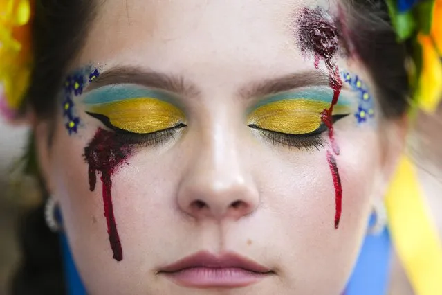 A woman made up with wounds and with Ukrainian colors attends a so called Freedom March demonstration, marking the Ukrainian Independence Day in Berlin, Germany, Wednesday, August 24, 2022. European leaders are pledging unwavering support for Ukraine as the war-torn country marks its Independence Day. The commemorations Wednesday coincide with the six-month milestone of Russia's invasion. (Photo by Markus Schreiber/AP Photo)