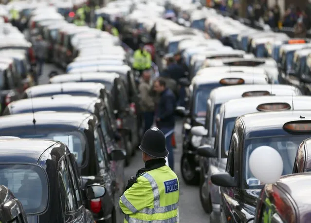 A police officer stands between rows of taxis during a protest by London cab drivers against Uber in central London, February 10, 2015. (Photo by Stefan Wermuth/Reuters)