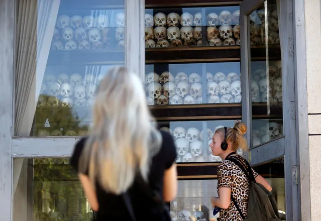 Tourists look at skulls and bones at the Choeung Ek memorial of more than 8,000 victims of the Khmer Rouge regime, at Choeung Ek “killing fields” site located on the outskirts of Phnom Penh, Cambodia, January 5, 2019. Picture taken on January 5, 2019. (Photo by Samrang Pring/Reuters)